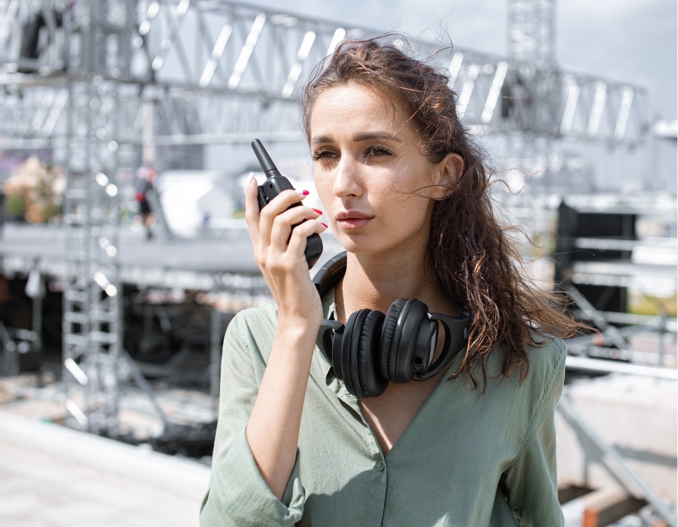 woman holding radio and wearing a headset coordinating an upcoming concert event